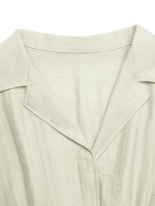 Detail of a beige linen shirt dress showing a classic Cuban collar and V-neckline texture