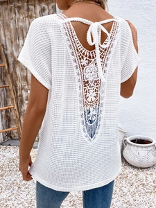 Close-up of bohemian white crochet top with V-back lace detailing and tassel ties