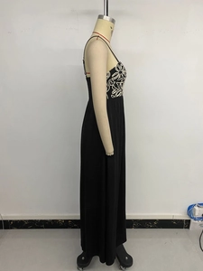 Détail de la broderie florale blanche sur une robe longue d'été noire sans manches
