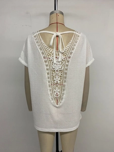 Detailed view of white textured lace patchwork back with V-neck and tassel ties