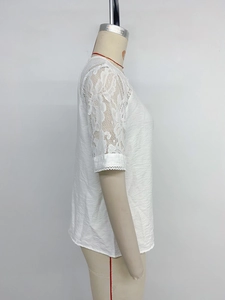 Detail of white round neck blouse showing floral lace patchwork on short sleeves
