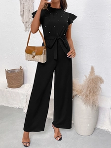 Detail of black wide-leg jumpsuit with ruffle sleeves and white pearl buttons decoration