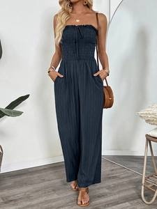 Detail of smocked bodice and decorative tie on navy blue wide-leg summer jumpsuit