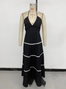 Detail of black pleated maxi dress showing white wavy lace trim and vertical texture