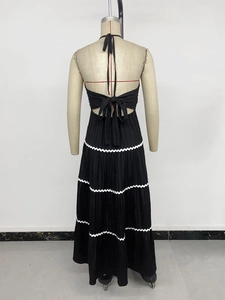 Detail of backless halter maxi dress with large bow tie and white wavy pleated hem