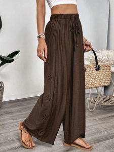Detailed view of dark brown wide-leg pants with floral cutout lace and drawstring waist