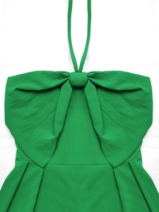 Dettaglio della tutina verde con scollo all'americana e un grande fiocco strutturato