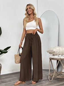 Detail of high-waist loose wide-leg trousers with intricate floral embroidery and drawstring