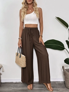 Detailed view of high-waist loose brown trousers with drawstring and hollow embroidery