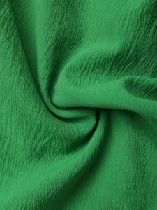 Vista macro del tessuto seersucker verde scuro con ricchi dettagli pieghettati sulla tuta