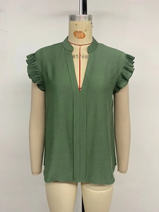 Detailed view of dark green V-neck top with pleated ruffle cap sleeves and textured fabric