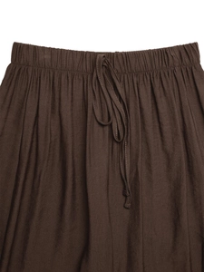 Detail of dark brown trousers featuring an elastic drawstring waist and linen texture