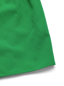 Dettaglio del tessuto a micro-rughe della tutina verde brillante con schiena scoperta