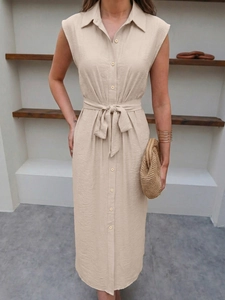 Detail of beige sleeveless shirt dress featuring lapel collar and adjustable waist belt