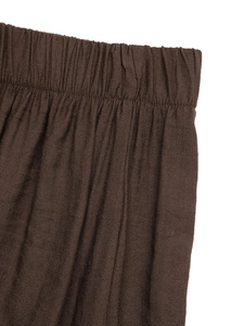 Detail of dark brown elastic waistband on wide-leg trousers with natural fabric texture