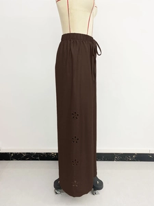 Detail showing brown wide-leg trousers with elastic drawstring waist and floral hollow embroidery