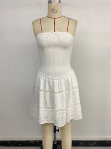 Detail of white smocked tube dress showing lace stitching and eyelet embroidery hem
