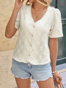 Detailed macro of white lace hollowed V-neck top featuring pearl buttons and floral hem
