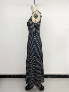 Détail d'une élégante robe longue noire à pois avec un col licou et un dos nu chic