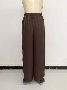 Detailed macro view of dark brown wide-leg trousers with elastic waist and fabric texture
