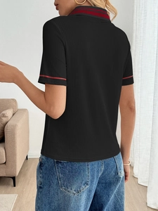 Detail of black polo shirt featuring vertical ribbed texture and red striped trim on sleeves