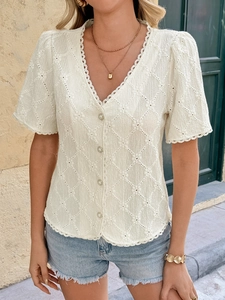 Close-up of white lace V-neck top featuring pearl buttons and delicate floral texture