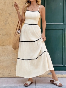 Close-up of tiered off-white maxi dress with delicate black lace trim and pleated bodice