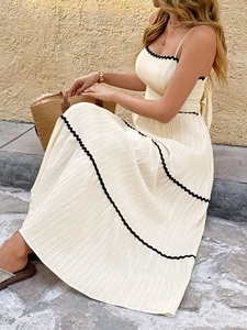 Detailed view of cream pleated maxi dress with contrasting black scallop edge trim
