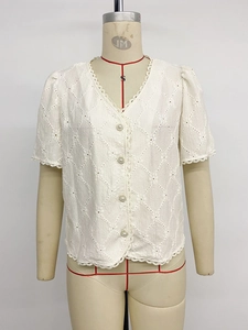 Close-up of white lace short sleeve shirt featuring pearl buttons and V-neckline