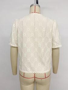 Detail of white lace-trimmed short sleeve blouse with diamond embroidery pattern