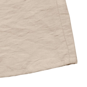 Macro detail of beige crepe fabric texture with neat stitching on a summer midi dress