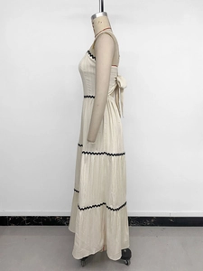 Detail view of cream tiered dress featuring black ric-rac trim and back bow knot tie