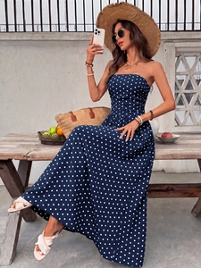 Close-up of navy blue polka dot strapless maxi dress with shirred waist in summer setting