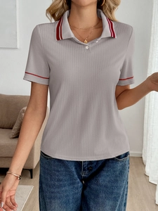 Detailed view of grey polo shirt featuring ribbed texture and red striped collar trim
