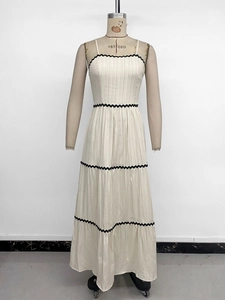 Detailed view of cream-white pleated dress with black wavy lace trim on the fabric