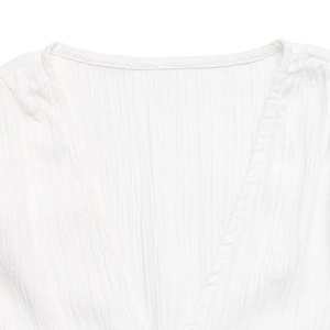 Detailed macro view of white V-neck shirt featuring vertical crinkle texture fabric