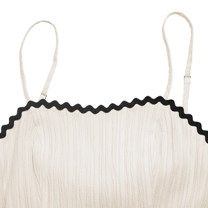 Detail of cream white dress with black scalloped trim and adjustable straps texture