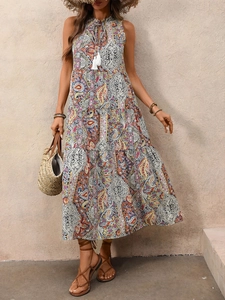 Détail d'une robe longue bohème à imprimé paisley, liens à glands et jupe à volants