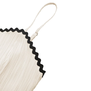 Close-up of cream strap top featuring black wavy lace trim and textured crepe fabric
