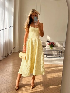 Close-up of elegant light yellow midi dress with 3D floral jacquard textured fabric