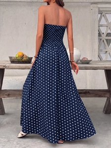 Detail showing the back of an elegant navy blue polka dot strapless maxi dress with smocking
