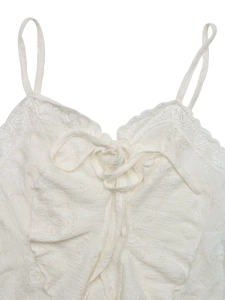 Close-up of white lace spaghetti strap top with delicate v-neck and ruffle details