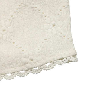 Detailed close-up of diamond textured fabric and intricate white lace embroidery trim