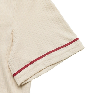 Detail of the ribbed knit sleeve cuff in cream color with a single red stripe accent
