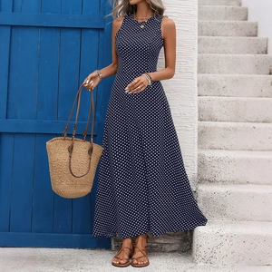 Détail d'une robe longue sans manches à pois bleu marine devant une porte rustique bleue