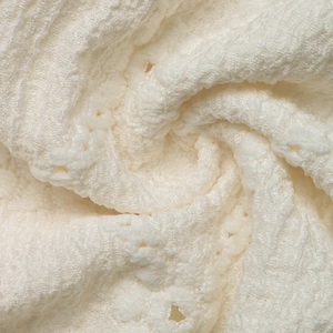 Macro shot of white waffle knit fabric with delicate lace crochet and hollow details