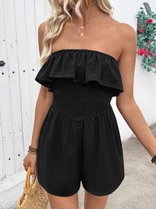 Detail of black strapless romper featuring ruffled neckline and smocked elastic waist