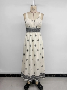 Detailed close-up of ethnic black embroidery on a beige cotton-linen midi dress