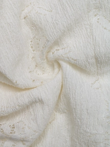 Detailed macro view of white lace fabric with intricate floral embroidery and textures