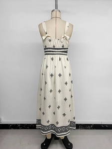Detail of bohemian cream maxi dress featuring black geometric embroidery and bow straps
